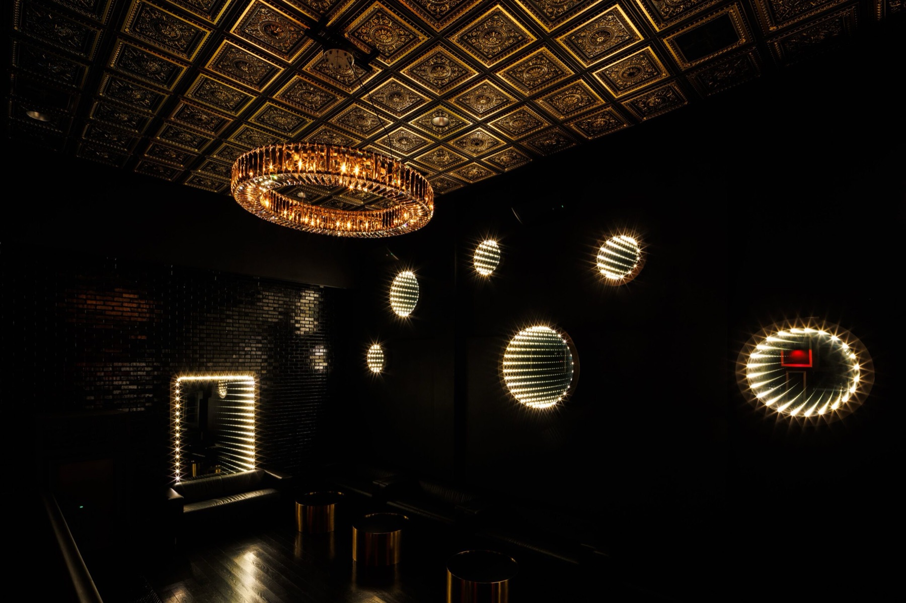 Studio Hundred, the third-floor party space at Ichibantei: a crystal chandelier, coffered ceiling and illuminated round mirrors over a dark lounge