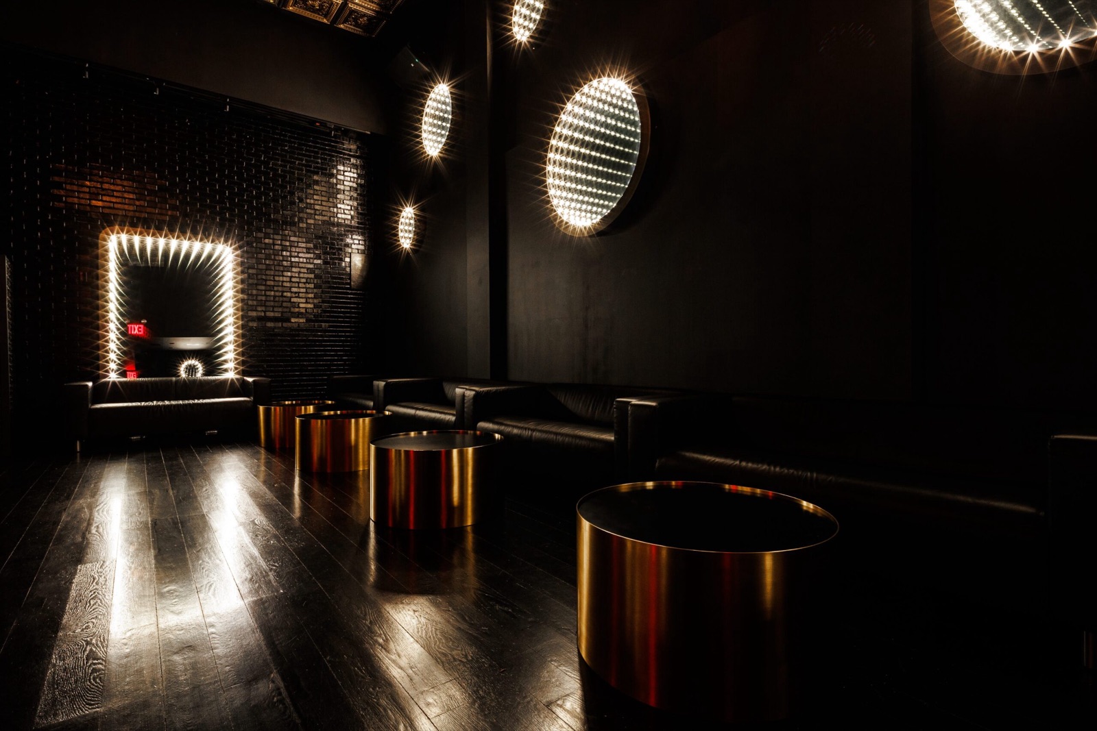 Black leather lounge seating and brass round tables at Studio Hundred