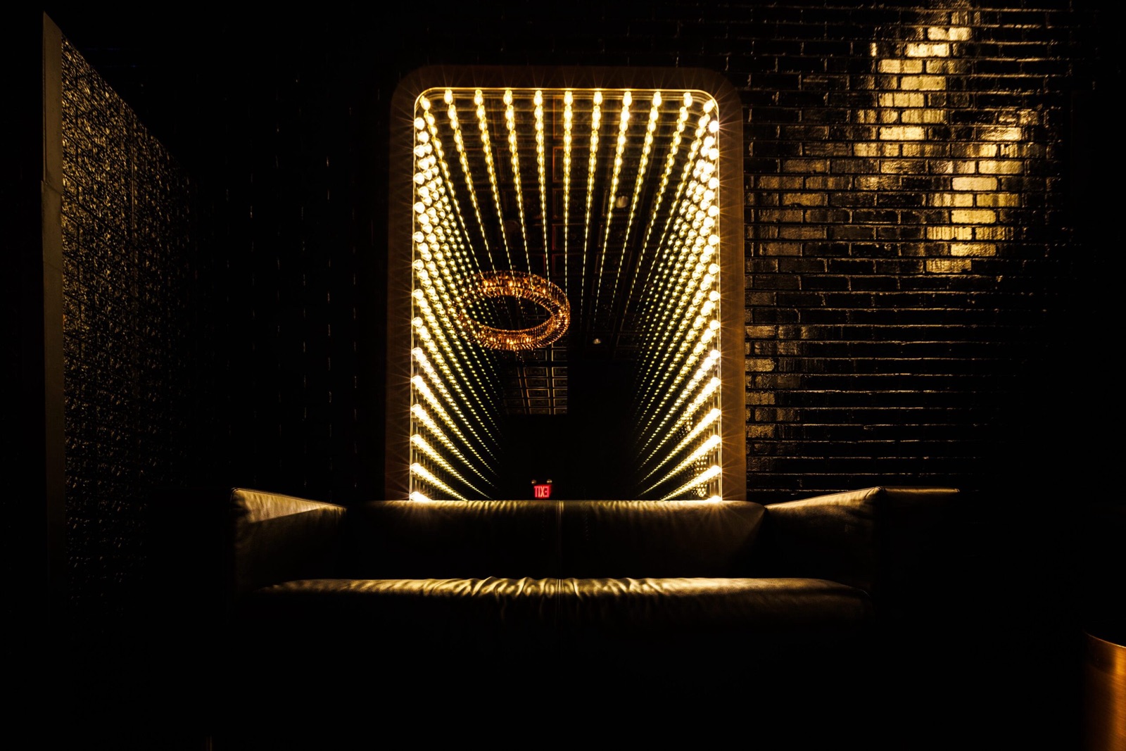Illuminated infinity mirror above a leather sofa at Studio Hundred